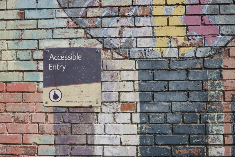 Accessible entry sign attached to a multicolour wall