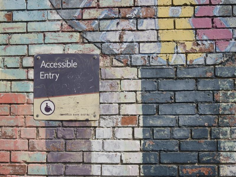 Accessible entry sign attached to a multicolour wall