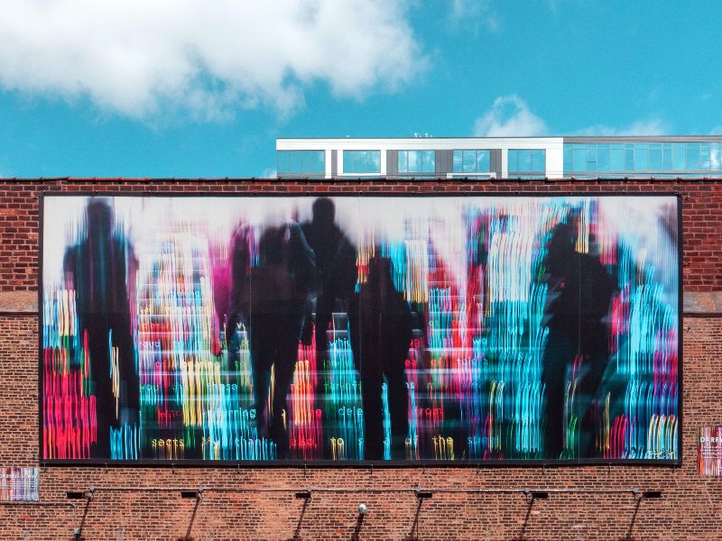 Abstract representation of coloured words and human figures on a poster on a wall
